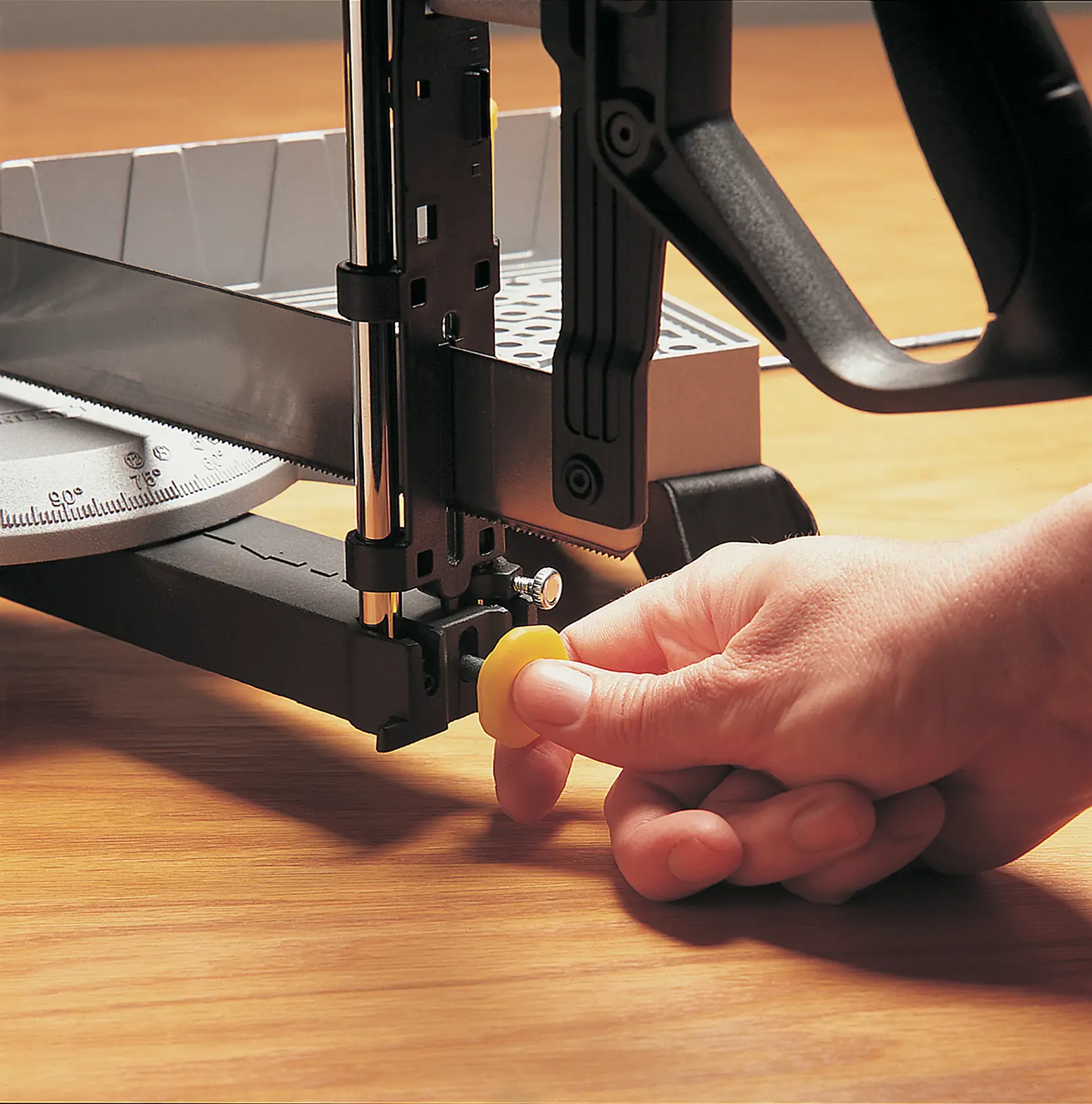 STANLEY 20-800 caja de ingletes primer plano con mano ajustando la perilla amarilla, herramienta sobre superficie de madera.