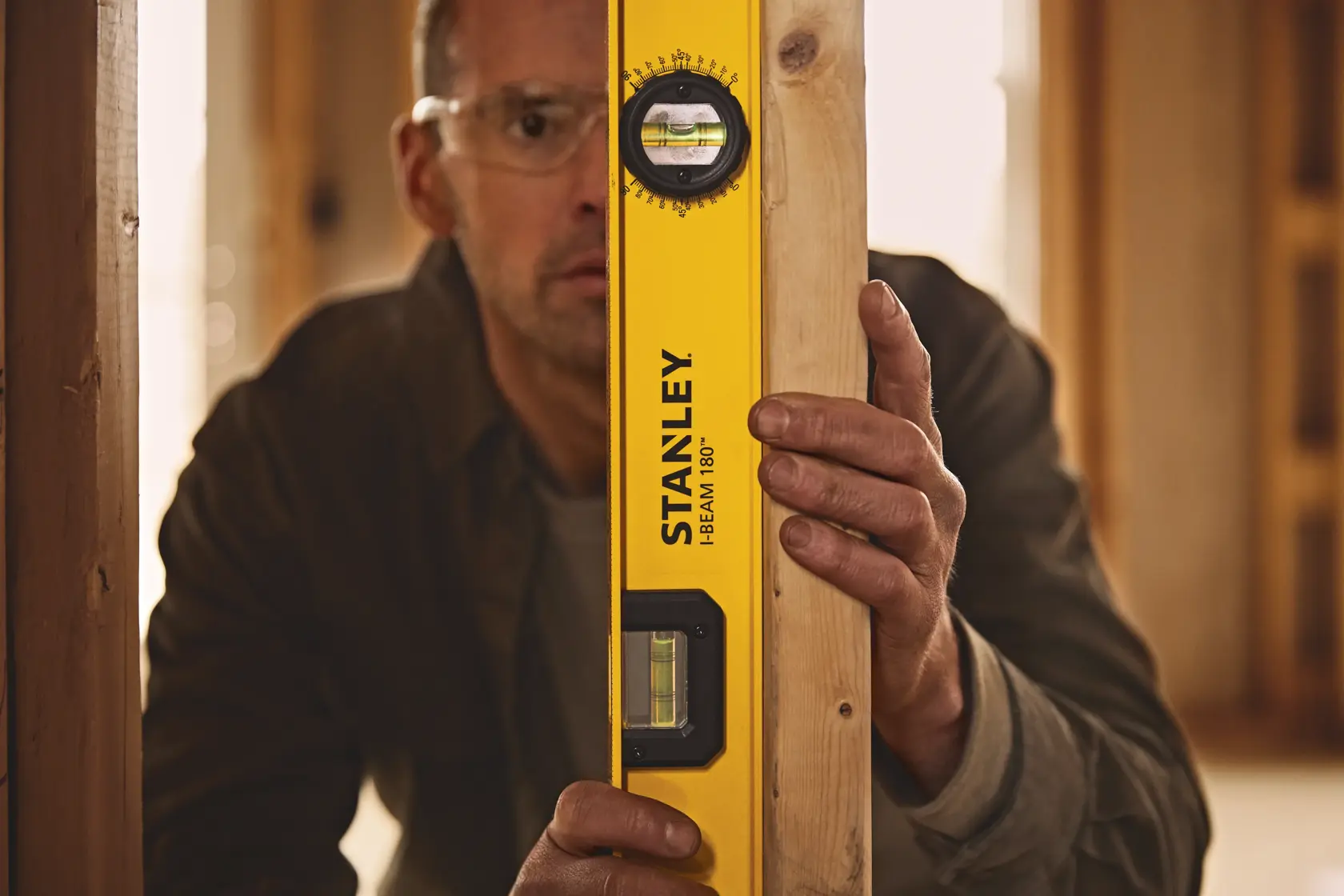 Fotografía del nivel STANLEY 42-324 I-Beam 180° sostenido contra una viga de madera en una obra.