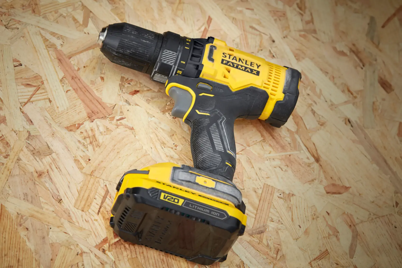 Taladro inalámbrico STANLEY SCD700C2K-B3 con diseño negro y amarillo, batería V20 de litio, en ángulo sobre superficie de madera.