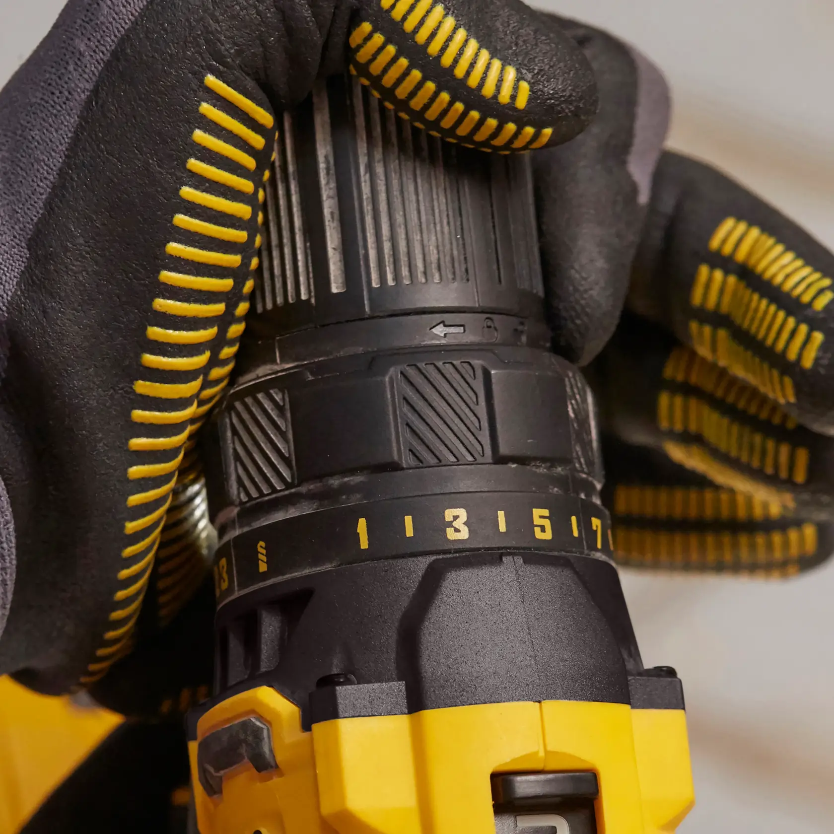 STANLEY SCD700C2K-B3 taladro en primer plano, trabajador ajustando configuración con guantes negros y amarillos.
