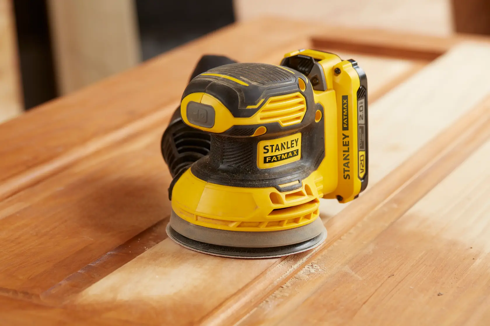 Lijadora inalámbrica STANLEY SCS220D1S-B2 amarilla y negra lijando una superficie de madera, vista de cerca.