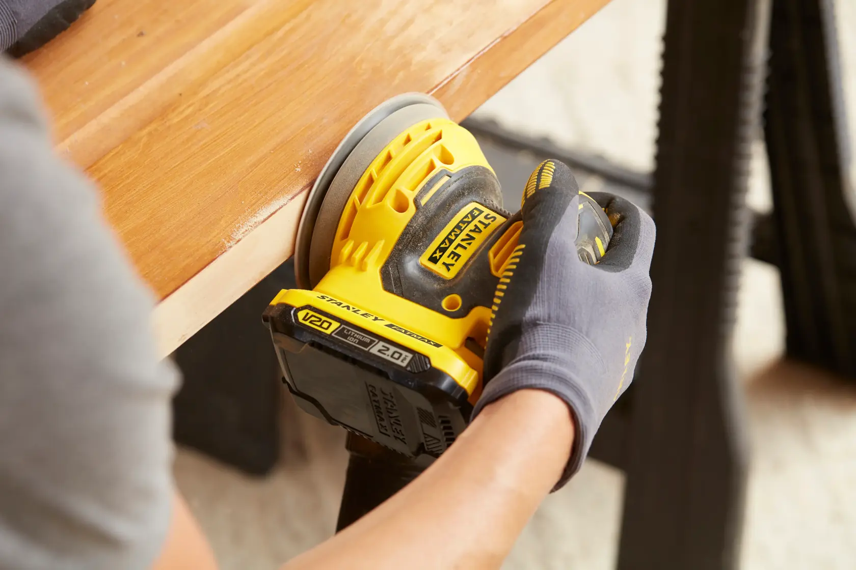 Stanley SCS220B lijadora inalámbrica usada sobre superficie de madera, ángulo cercano.