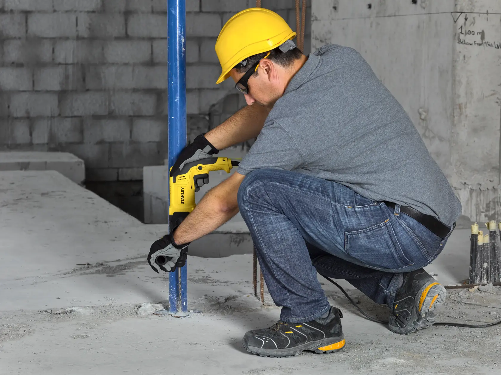 Martillo rotatorio Stanley SHR263K-BR en uso durante instalación de piso, trabajador con equipo de seguridad.