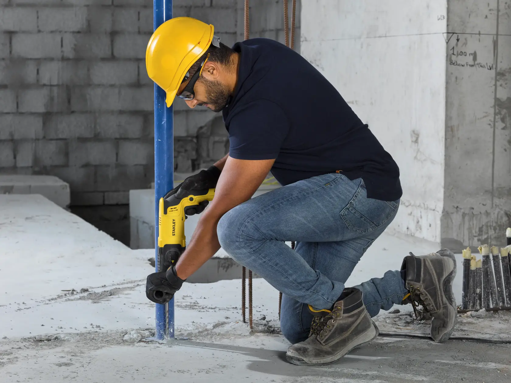 Taladro rotomartillo STANLEY SHR263K-BR en uso sobre madera, operario con casco amarillo y uniforme negro.