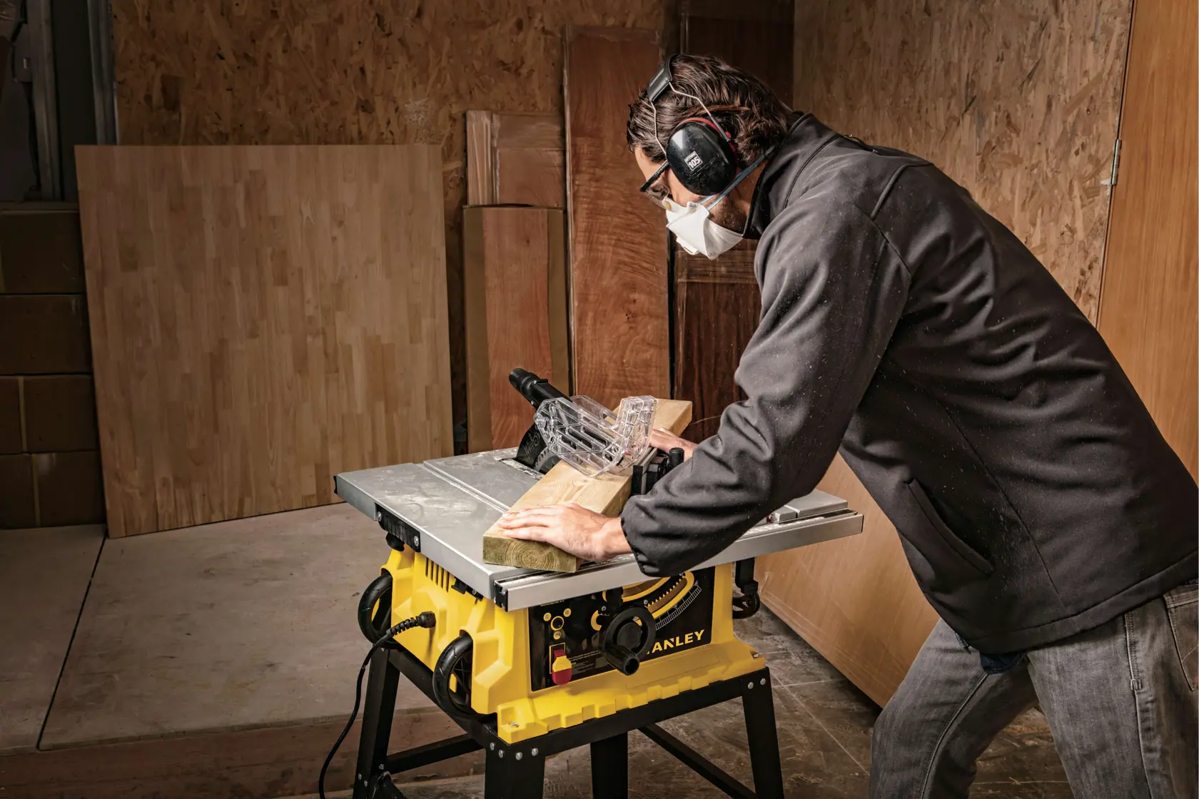 Sierra de mesa Stanley SST1801-B3 en uso, cuerpo amarillo, cortando madera en taller.