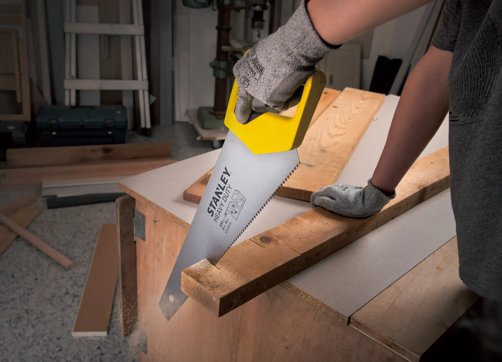 Fotografía de sierra manual STANLEY STHT20375-LA con mango amarillo cortando madera, producto en uso en taller.