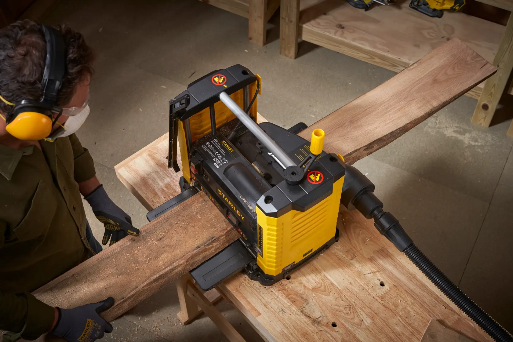 Fotografía de la cepilladora STANLEY STP18-B2 en uso, alisando una tabla de madera en un taller desde arriba.
